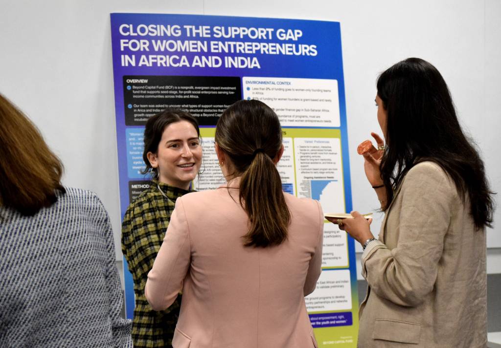 one student showing a poster to two other students