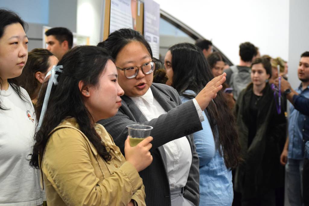 one student pointing to something standing next to another student