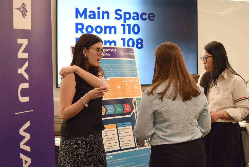 a student presenting a poster to two other students